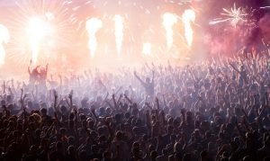 Cheering crowd at concert in front of stage with pyrotechnics